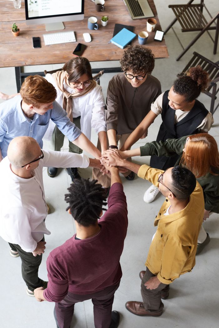 Crafting Captivating Headlines: Your awesome post title goes here A diverse group of professionals joins hands in a team-building exercise indoors.